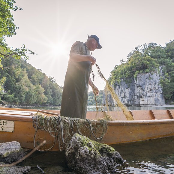 Donaufischer Heinrich Ziegler in seinem Boot am Donaudurchbruch in der Weltenburger Enge. Er sortiert gerade seine Fischernetze.