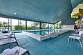 Hallenbad im ABG Tagungszentrum Ein großer Indoor Pool mit blauen Fliesen und Liegestühlen mit Sonnenschirmen.